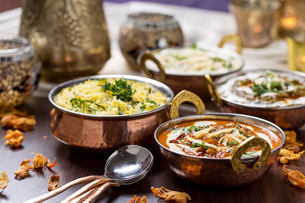 Copper karahi dishes of biryani and butter chicken on a decorated table